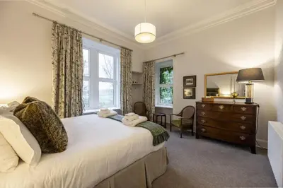 a bedroom with a bed and a dresser and a window at Cairns Farmhouse in Kirknewton