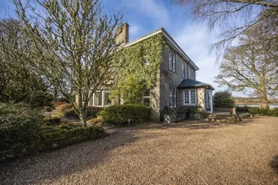 an exterior view of a house with a large yard at Cairns Farmhouse in Kirknewton