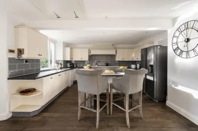a kitchen with white cabinets and a black refrigerator at Cairns Farmhouse in Kirknewton
