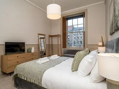a bedroom with a bed and a tv and a window at Pass the Keys Beautiful Modern Historical Flat Close to Castle in Edinburgh
