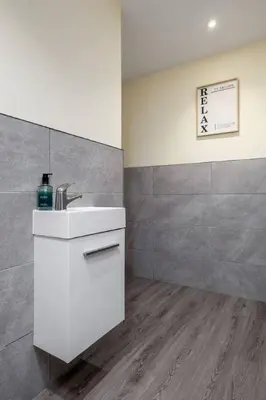 a bathroom with a white sink and a tile wall at Stirlings Hidden and Tranquil Studio Apartment in Stirling