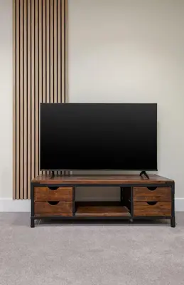 a flat screen tv sitting on top of a wooden entertainment center at Stirlings Hidden and Tranquil Studio Apartment in Stirling