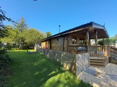 a wooden cabin with a fence in front of it at 87 Loch Murray in Creetown
