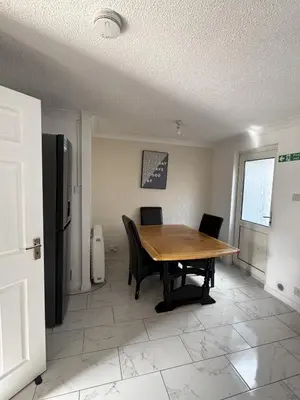 a dining room with a table and chairs and a refrigerator at Honey House in Moffat