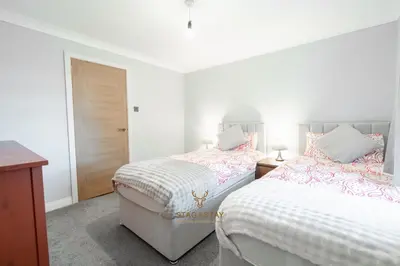two beds in a bedroom with white walls at Stag & Stay- Waterlillie - Contractor friendly, Fast WiFi in Port Glasgow