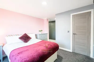 a bedroom with a bed with a pink blanket at Stag & Stay- Waterlillie - Contractor friendly, Fast WiFi in Port Glasgow