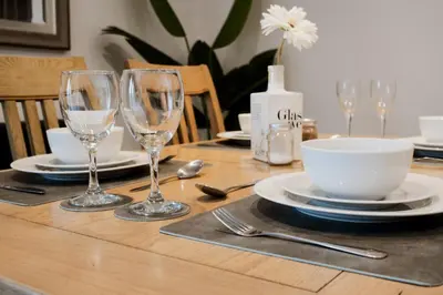 a wooden table with plates and glasses on it at Stag & Stay- Waterlillie - Contractor friendly, Fast WiFi in Port Glasgow