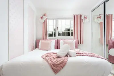 a bedroom with a large white bed with pink curtains at No22 Shalloch House - Donnini Apartments in Ayr