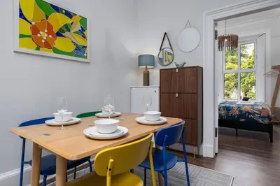 a dining room with a wooden table and blue chairs at Stirling Retreat Quirky Decor, Fireplace and Charm in Stirling