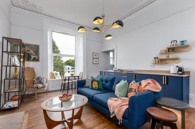 a living room with a blue couch and a table at Stirling Retreat Quirky Decor, Fireplace and Charm in Stirling