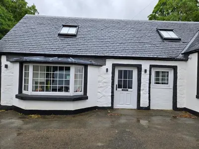 a white house with a window and a door at The Tearoom Tarbet in Tarbet