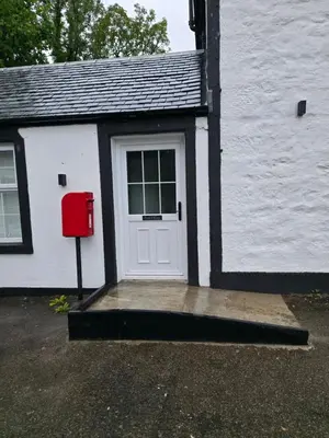 a white house with a white door and a red mailbox at The Post Office Tarbet in Tarbet