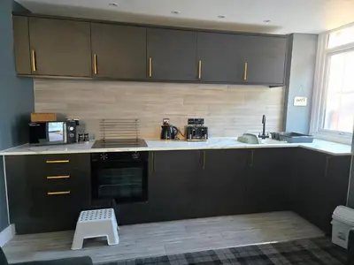 a kitchen with black cabinets and a white stool at The Post Office Tarbet in Tarbet
