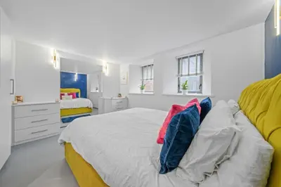 a white bedroom with a large bed with colorful pillows at Unique 1 Bedroom Near West End in Glasgow
