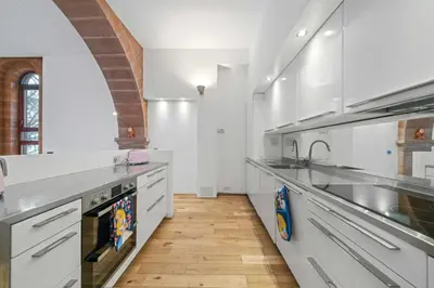a large white kitchen with white cabinets and a wooden floor at Unique 1 Bedroom Near West End in Glasgow