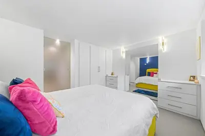 a white bedroom with a bed with colorful pillows at Unique 1 Bedroom Near West End in Glasgow
