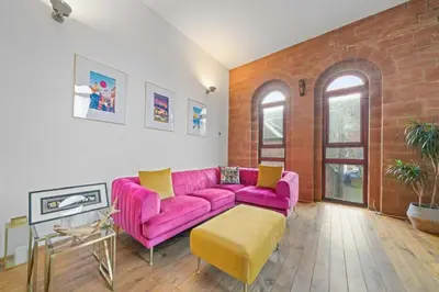 a pink couch in a living room with a brick wall at Unique 1 Bedroom Near West End in Glasgow