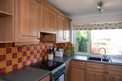 a kitchen with wooden cabinets and a sink and a window at 70 Abbotsbury Road, Bury St Edmunds, IP33 2HP in Moffat