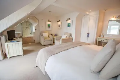 a bedroom with a white bed and a living room at Glenisle Hotel in Isle of Arran