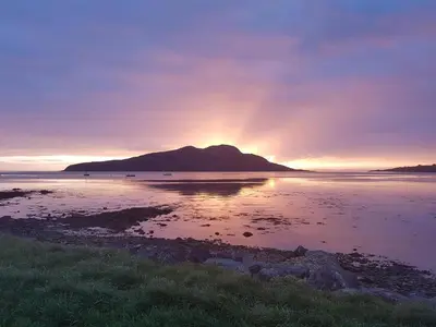 a sunset over a body of water with a mountain at Glenisle Hotel in Isle of Arran
