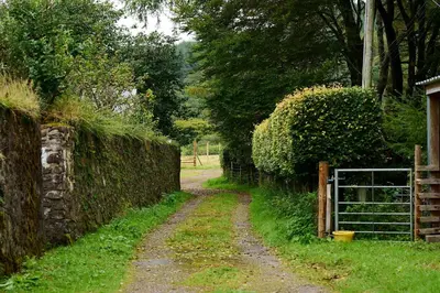 a dirt road next to a fence with a gate at Rural 1-Bed Retreat at Stunning Raera Farm in Kilninver