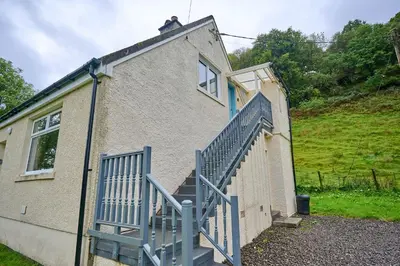 a building with a blue staircase next to a house at Rural 1-Bed Retreat at Stunning Raera Farm in Kilninver