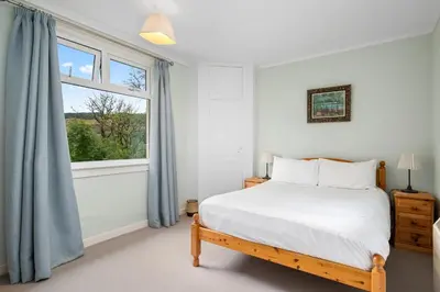 a white bedroom with a bed and a window at Charming 2-Bed Cottage on Tranquil Raera Farm in Kilninver