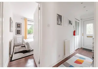 a white room with a hallway with a bed and a mirror at Elegant Flat in a Serene Edinburgh Neighbourhood in Edinburgh