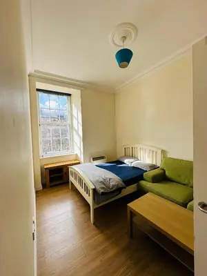 a bedroom with a bed and a green couch at Cozy Room In Sauchiehall Street in Glasgow