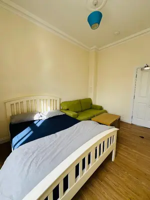 a bedroom with a large bed and a green couch at Cozy Room In Sauchiehall Street in Glasgow