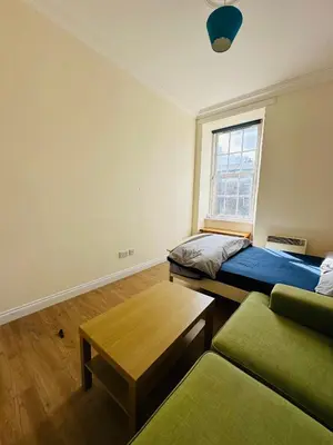 a room with a bed and a couch and a window at Cozy Room In Sauchiehall Street in Glasgow