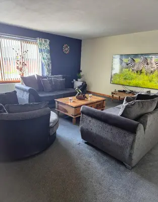 a living room with couches and a flat screen tv at The Yard Bungalow in Sanquhar