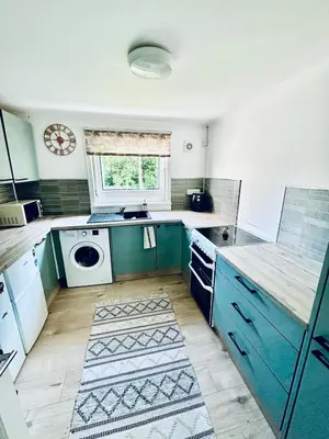 a kitchen with blue cabinets and a washing machine at 3 bedroom apartment in Cumbernauld