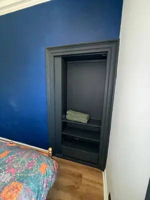 a bedroom with a blue wall and a shelf at 3 bedroom traditional apartment in Ayr