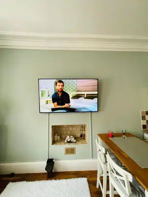 a tv hanging on a wall with a fireplace at Lovely 2 bedroom apartment in Ayr town centre in Ayr