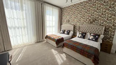 a bedroom with two beds and a chair and windows at Armadillo Guest House- Adults Only in Edinburgh