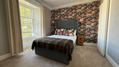 a bedroom with a bed with a floral wallpaper at Armadillo Guest House- Adults Only in Edinburgh