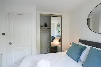 a bedroom with a white bed with blue pillows and a mirror at Modern 2 Bedroom Platinum Pad Glasgow City in Glasgow