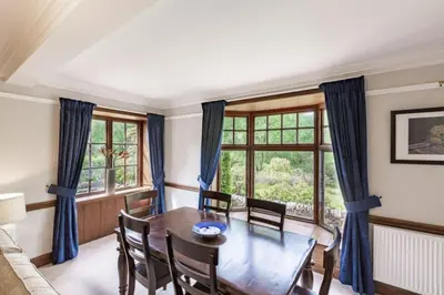 a dining room with a table and chairs and a window at Lonan Country House and Gardens in Taynuilt