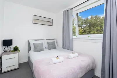two beds in a bedroom with a window at Livingston Retreat 4bed Home Wi-Fi Parking in Uphall