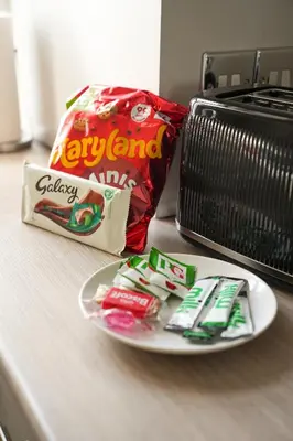a plate of candy and a bag of chips next to a toaster at Neilston Apartment in Paisley