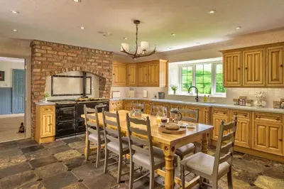 a kitchen with a wooden table and chairs and a fireplace at Finest Retreats - Grassyards House in Largs