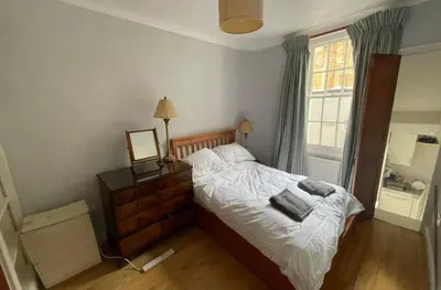 a bedroom with a bed with white sheets and a window at Central and Spacious first floor flat in Moffat