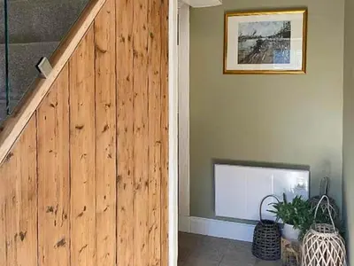 a hallway with a wooden wall with a staircase and a television at Monawilline Cottage in Lamlash