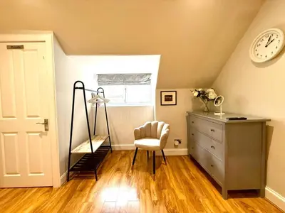a room with a chair and a dresser and a clock at Historic Mews House 2BR in Edinburgh City Centre in Edinburgh