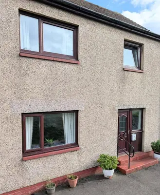 a house with three windows and potted plants in front at Kintyre House in Campbeltown