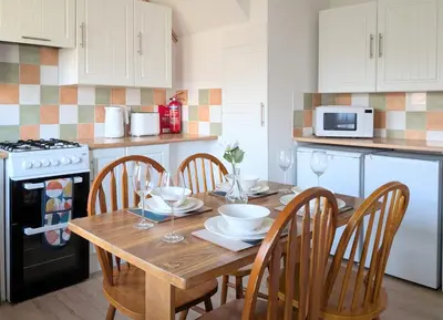a kitchen with a wooden table with chairs and a microwave at Kintyre House in Campbeltown