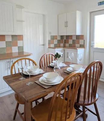 a kitchen with a wooden table with chairs and wine glasses at Kintyre House in Campbeltown