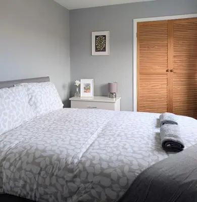a bedroom with a bed and a wooden closet at Kintyre House in Campbeltown