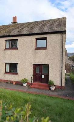 a house with a red door and two potted plants at Kintyre House in Campbeltown